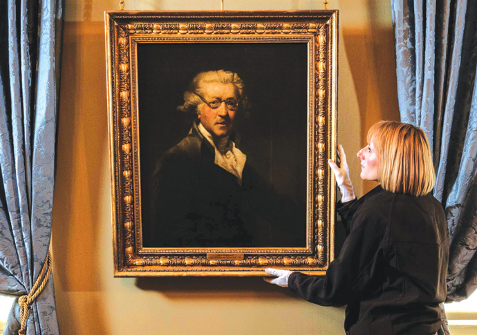 English Heritage curator Louise Cooling positions Joshua Reynold’s self-portrait. The painting features in a new display marking 300 years since the birth of the celebrated